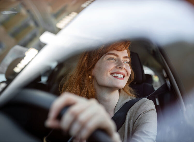 Smiling woman driving a car, viewed through the windscreen